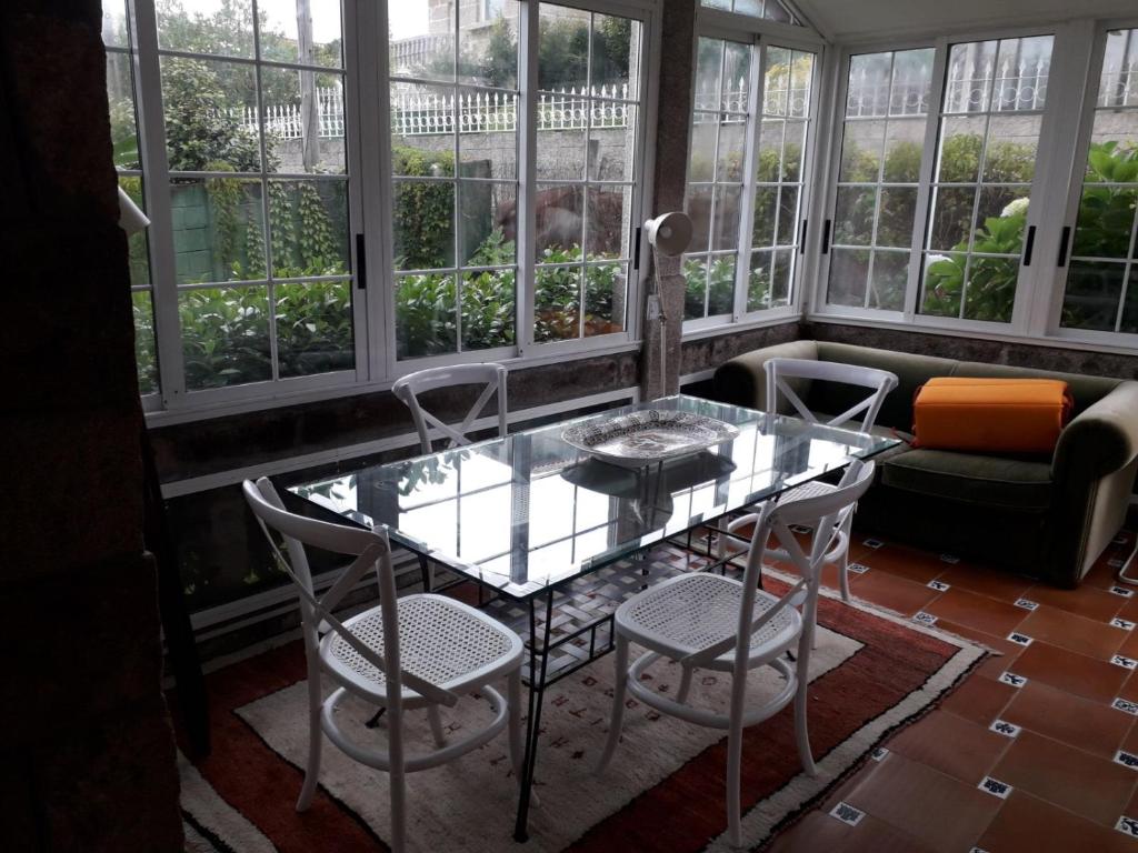 une table et des chaises en verre dans une pièce avec fenêtres dans l'établissement Casa Magda, à Vigo