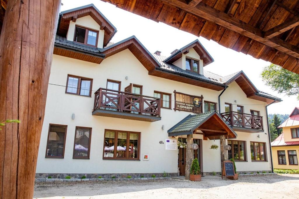 Karczma Karnasów في تشيسنا: منزل في الجبال مع نوافذ وشرفات