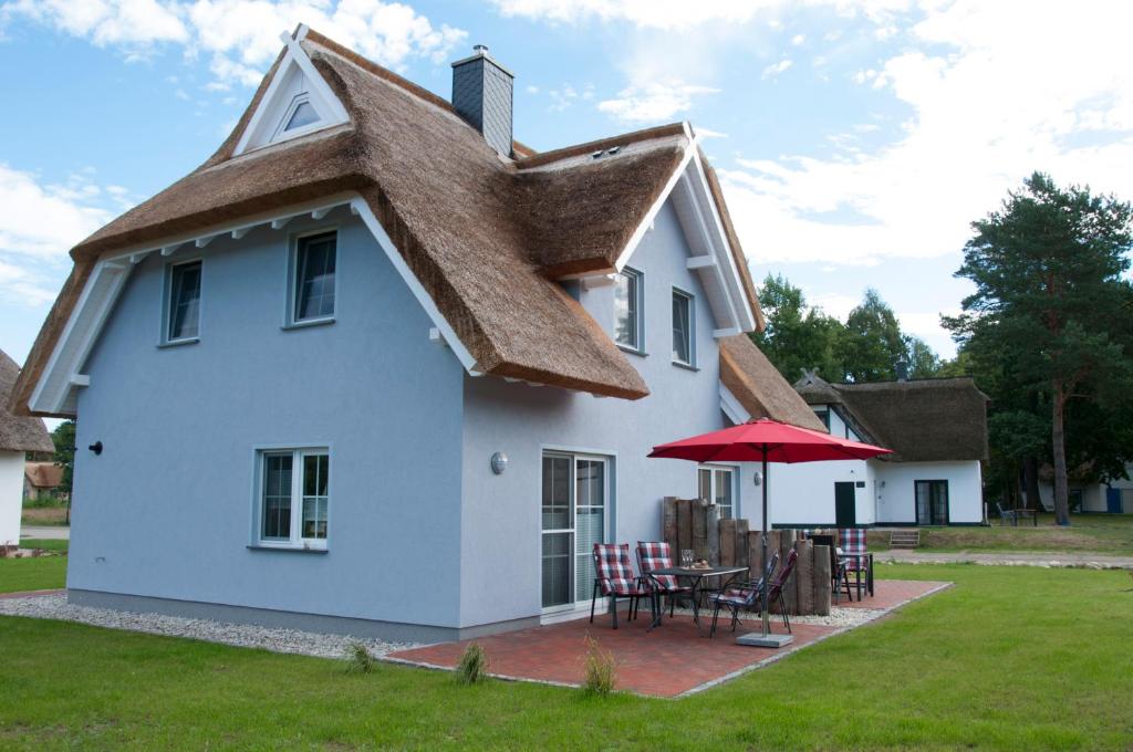 una casa bianca con tetto di paglia, tavolo e sedie di Haus Steuerbord a Zirchow