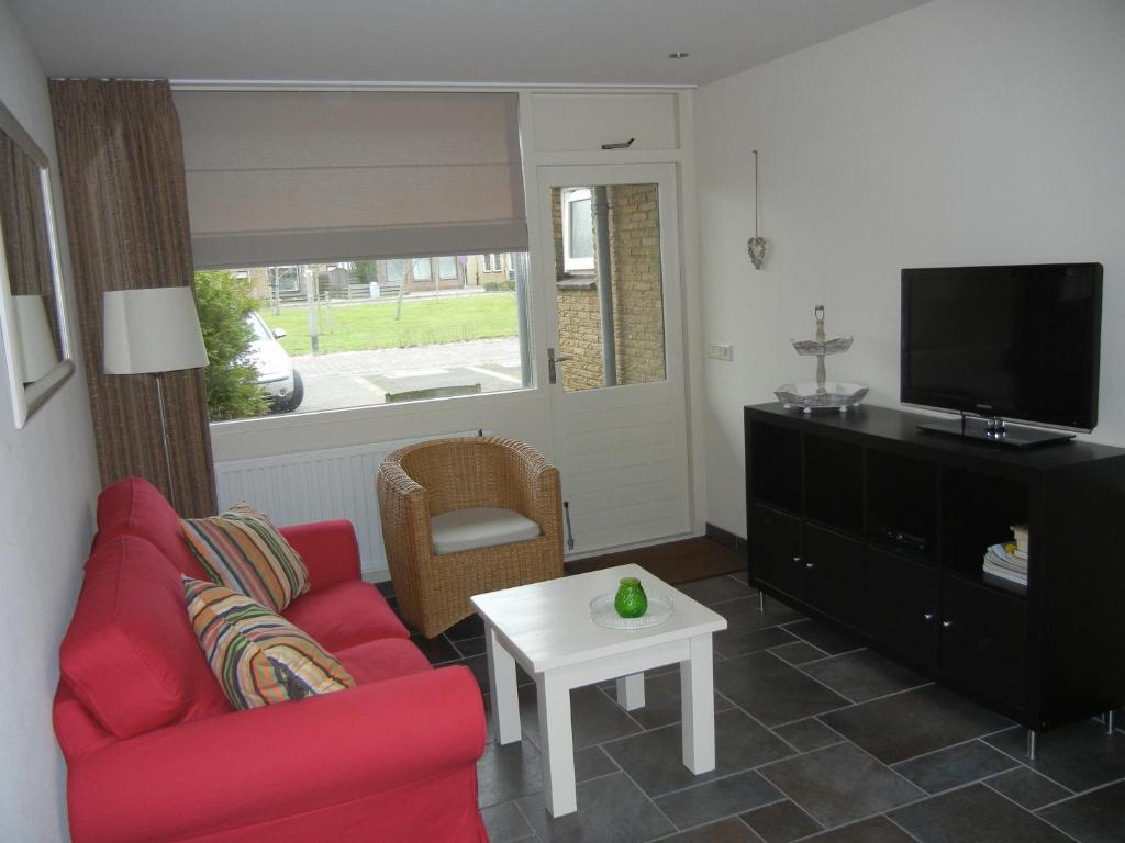 a living room with a red couch and a tv at Mooi zo 2 in De Koog