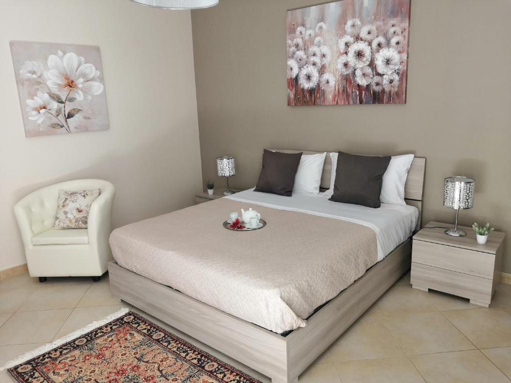 a bedroom with a large bed and a chair at Sicilian Panoramic Apartment in Floridia