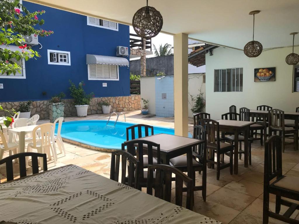 a patio with tables and chairs and a swimming pool at Pousada Pé na Areia in Pipa