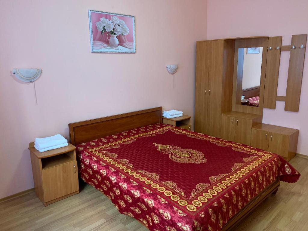 Schlafzimmer mit einem Bett mit einer roten Tagesdecke und einem Spiegel in der Unterkunft Inn on Zhytomyrska in Kiew