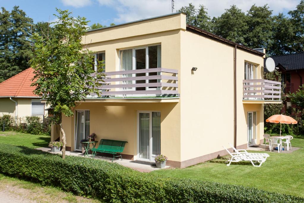 a house with a green bench in the yard at Villa LILIA in Międzywodzie