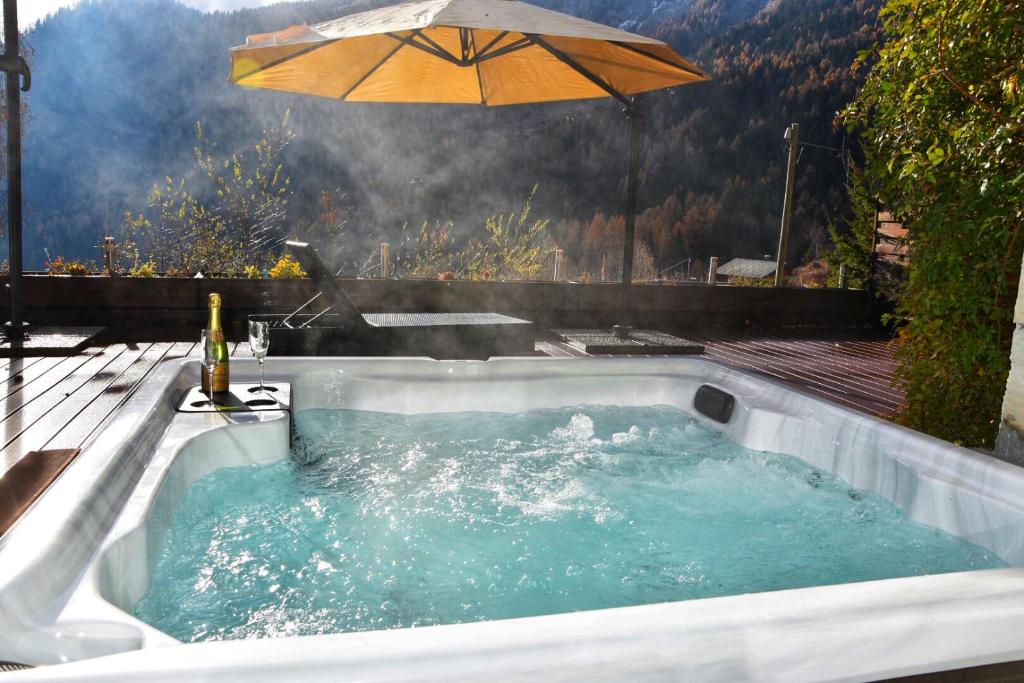 a hot tub with an umbrella on a deck at Chalet Belmont in Ovronnaz
