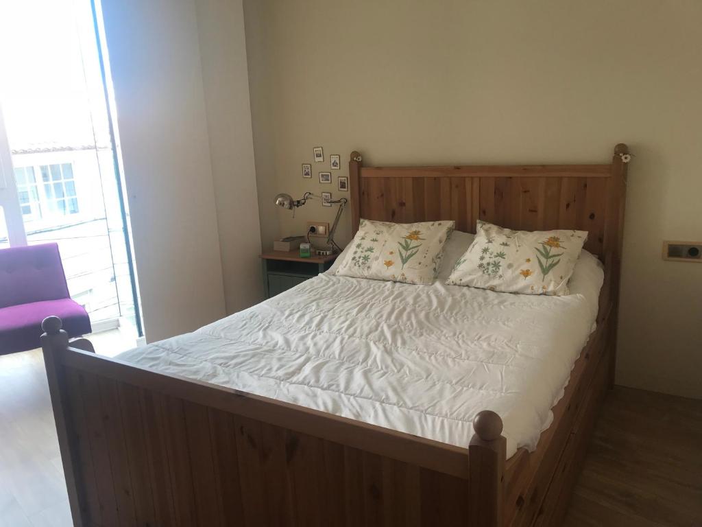 sypialnia z drewnianym łóżkiem z białą pościelą i poduszkami w obiekcie Preciosa Casa en el Casco Histórico de Baiona w mieście Baiona