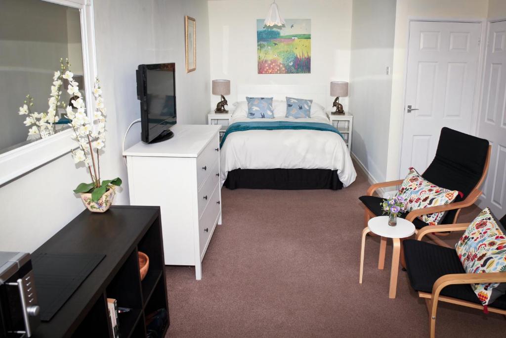 sypialnia z łóżkiem, telewizorem i kanapą w obiekcie Lowerbourne House Studio w mieście Porlock
