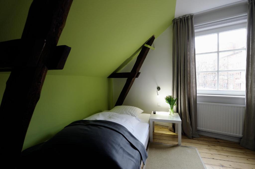 Dormitorio verde con cama y ventana en Hotel KUHBERG Hamburg, en Hamburgo