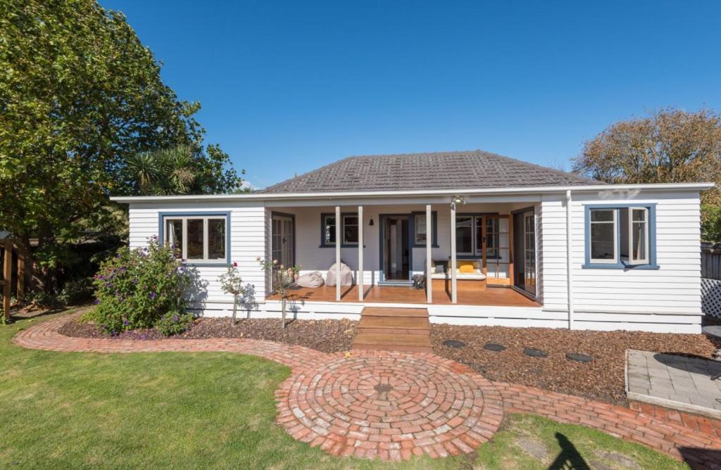 een wit huis met een bakstenen pad in de tuin bij Morning Bloom Cottage Bed and Breakfast in Nelson