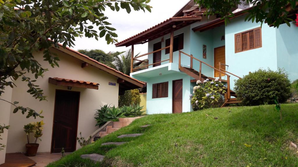 una casa con un césped verde delante de ella en Chalé & Suítes Mar Aberto en Ilhabela