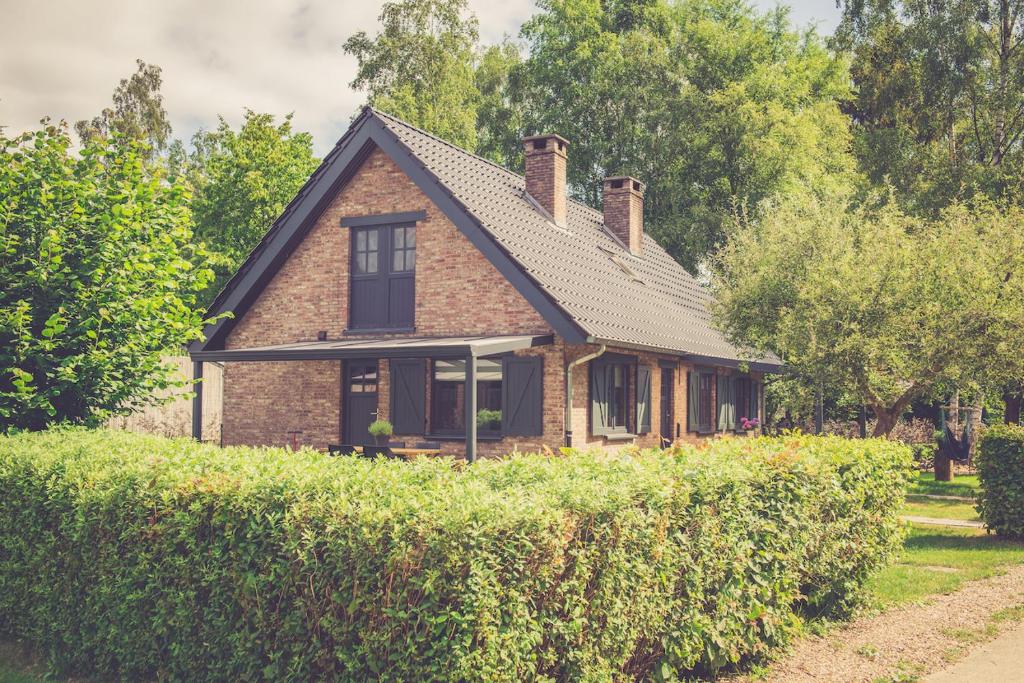 una casa de ladrillo con techo sobre un seto en Landhuisjes Bij De Wouterbron en Opglabbeek