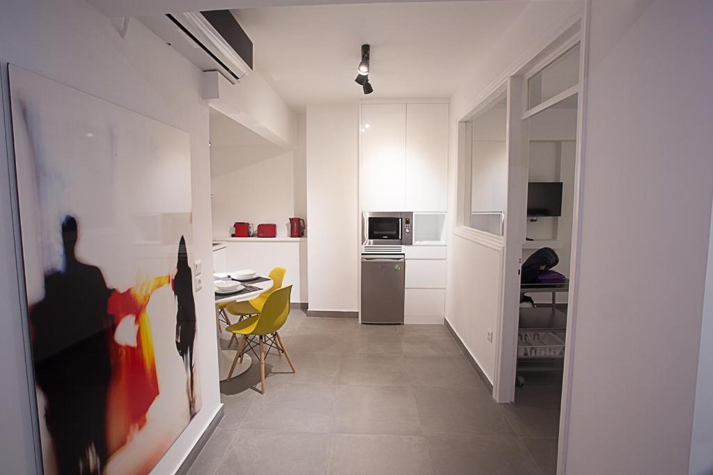 - une cuisine blanche avec une table et des chaises jaunes dans l'établissement Dimokritou 4 Apartment, à Athènes
