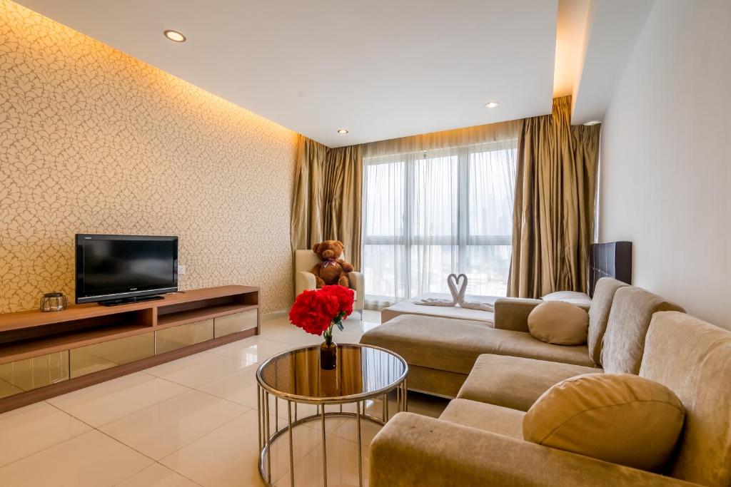 ein Wohnzimmer mit einem Sofa und einem TV in der Unterkunft Regalia Residence @ KLCC View Sky Pool by MC in Kuala Lumpur