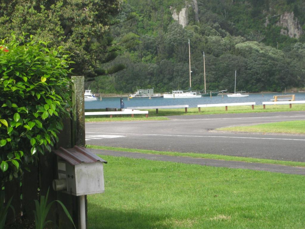 a road next to a body of water with boats at Harbour Inn in Whangamata
