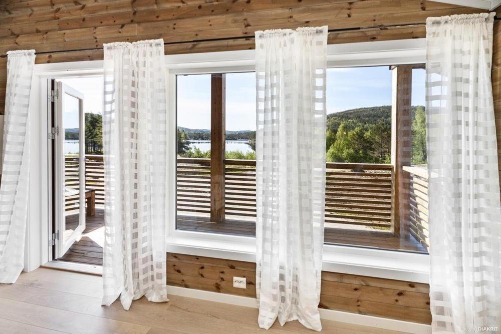 um quarto com uma grande janela com cortinas brancas em Bjørndalsvatnet em Hornnes