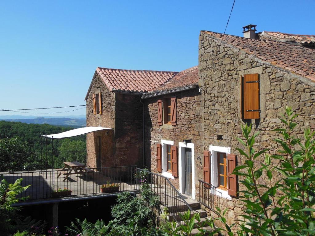 a stone house with a balcony and a table at Grand Gîte à la ferme in Les Costes-Gozon