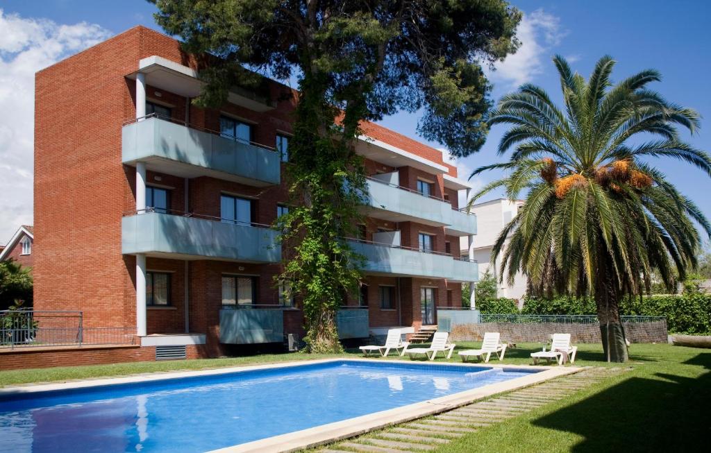an apartment building with a swimming pool in front of a building at SG Costa Barcelona Apartments in Castelldefels
