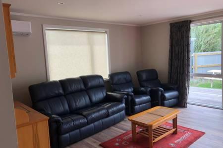 a living room with a black leather couch and chairs at Park-Inn Lodge in Dorie