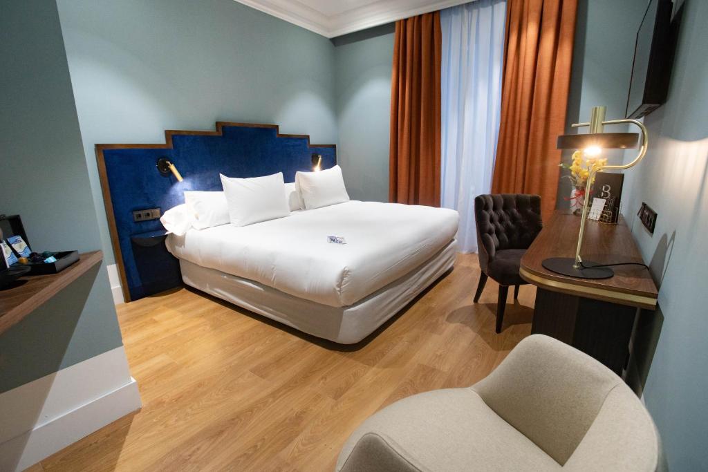 una camera d'albergo con letto, scrivania e sedia di Soho Boutique Congreso a Madrid