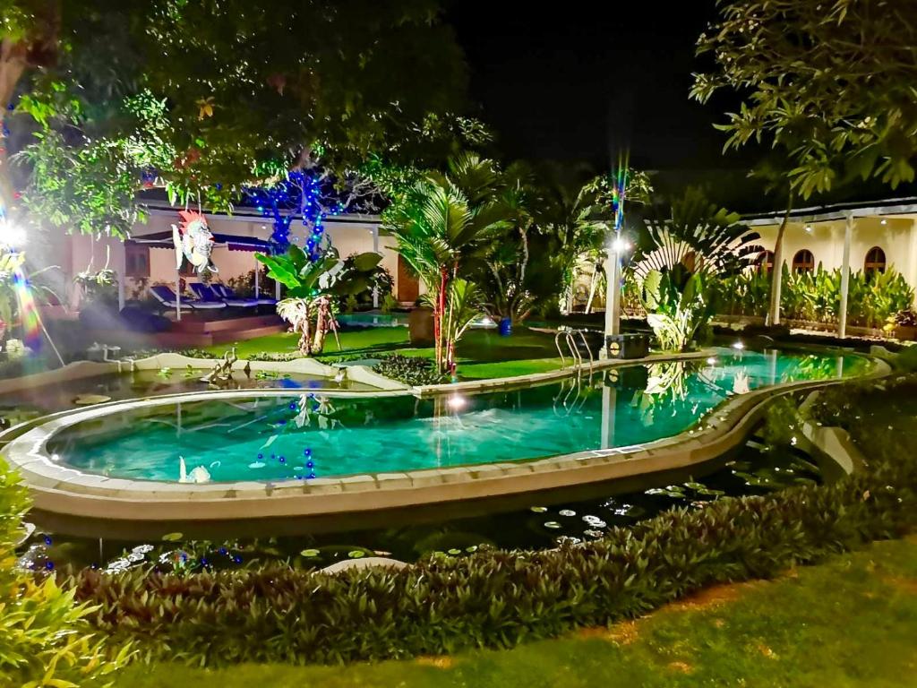 ein Schwimmbad in einem Garten in der Nacht in der Unterkunft Villa Costa Plenty in Sanur