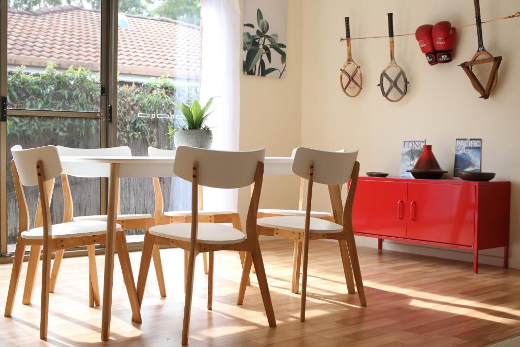 jadalnia ze stołem i krzesłami oraz czerwoną szafką w obiekcie Two 46 Brodie w mieście Coffs Harbour