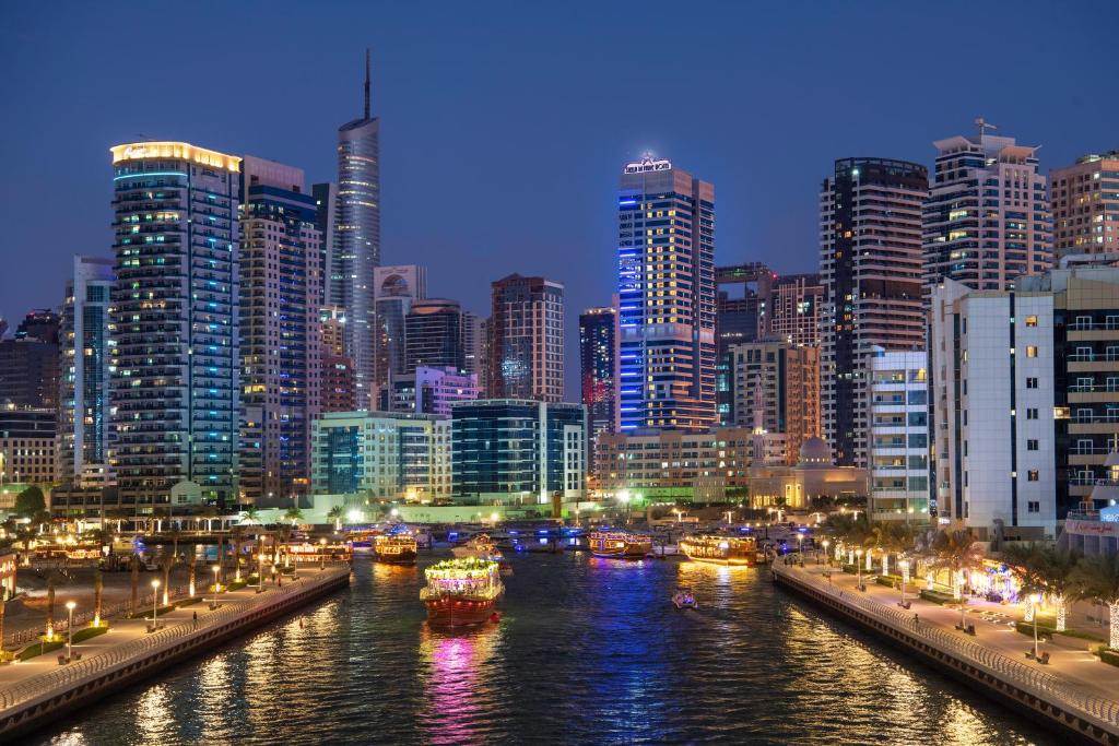 una città di notte con barche in acqua di Stella Di Mare Dubai Marina Hotel a Dubai