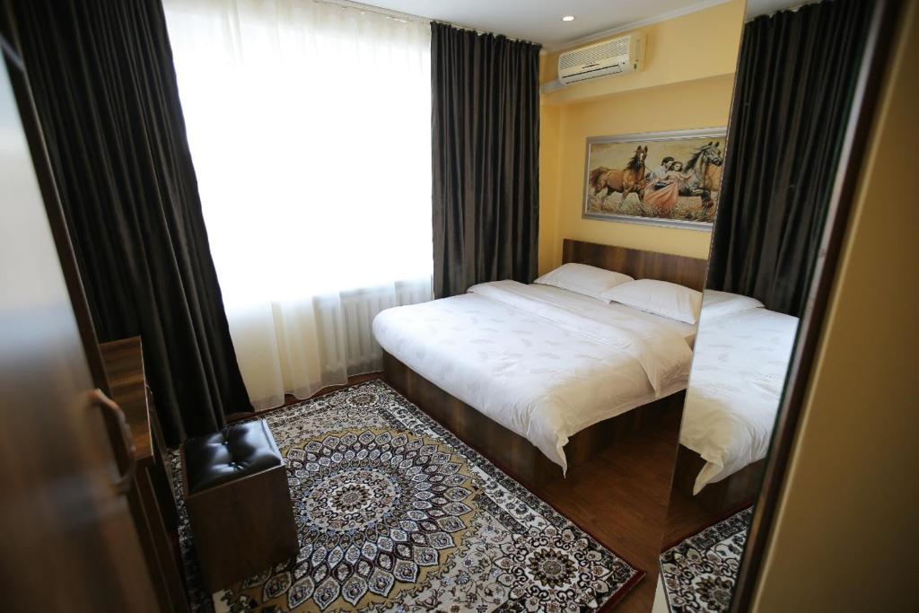 a bedroom with two beds and a large window at Altai Business Hotel in Almaty