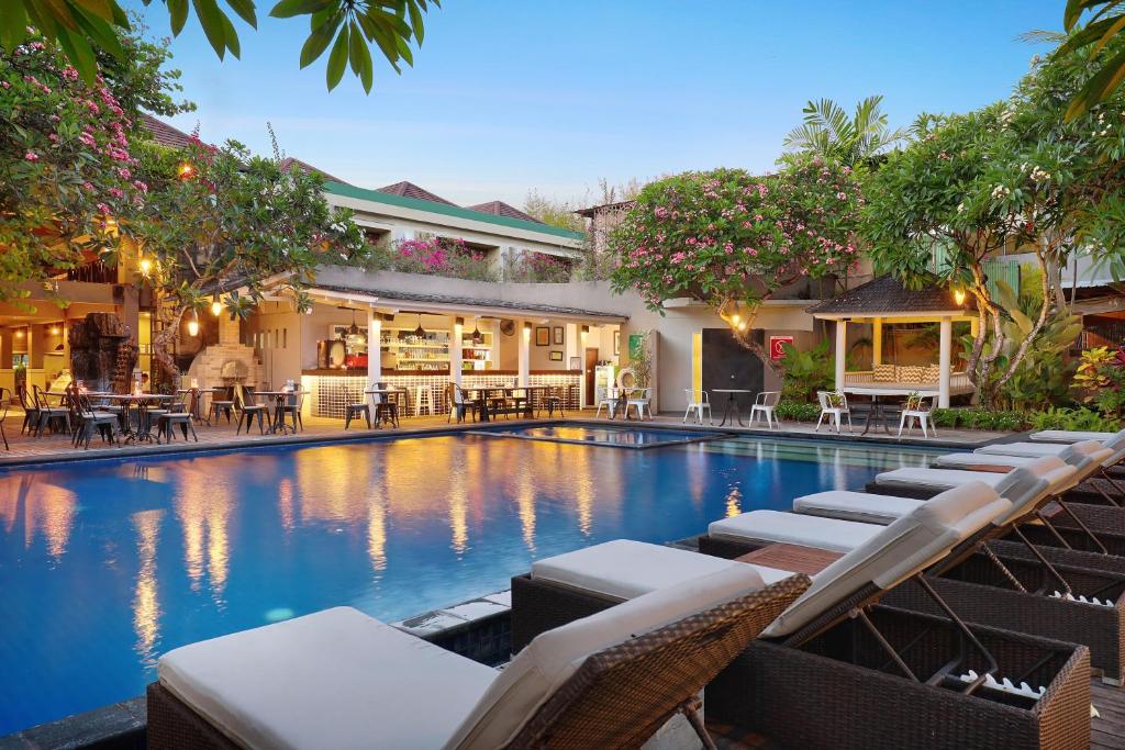 uma piscina com cadeiras e mesas em frente a um edifício em Sagara Villas and Suites Sanur em Sanur