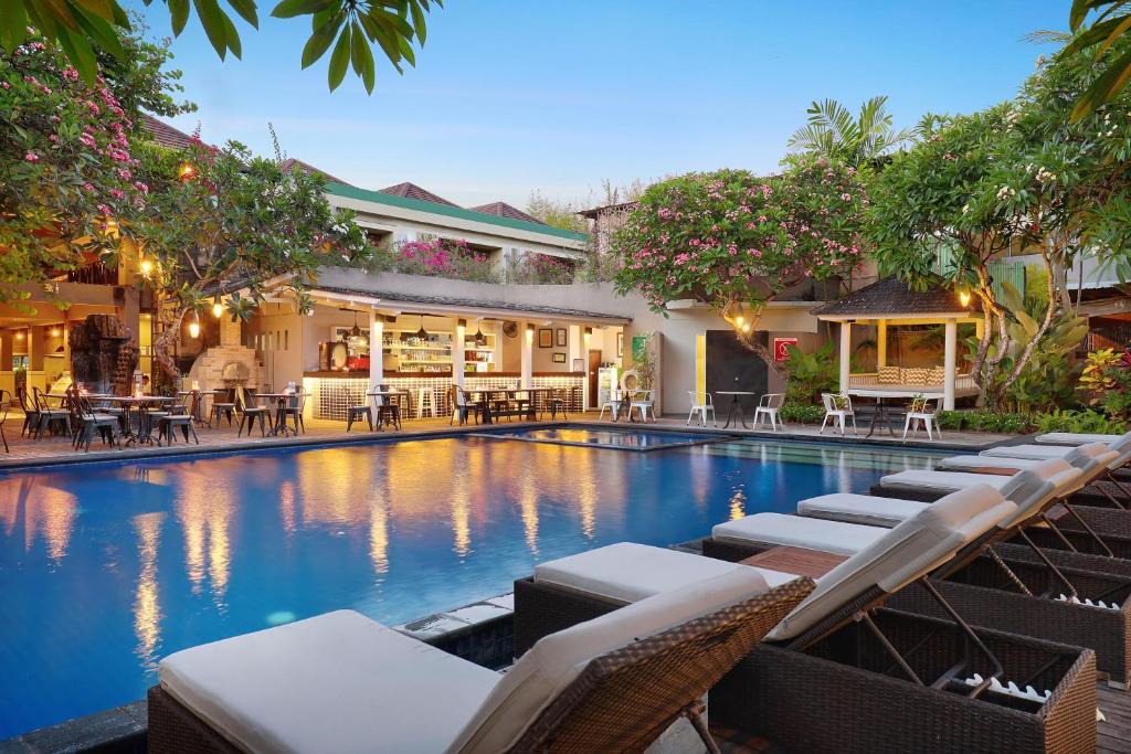 a swimming pool with chairs and tables in front of a building at Sagara Villas and Suites Sanur in Sanur