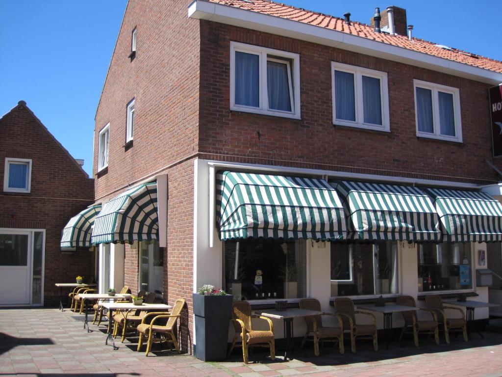 
a patio area with chairs, tables and umbrellas at Hotel Valkenhof in Zoutelande
