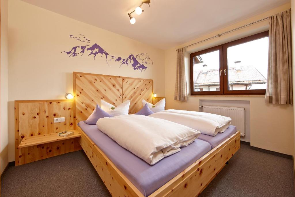 Schlafzimmer mit einem großen Bett mit einem Kopfteil aus Holz in der Unterkunft Gästehaus Alpina in Bad Kohlgrub