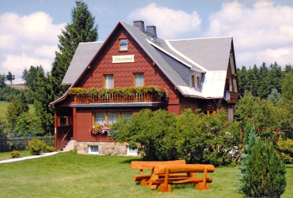 une maison avec un banc devant elle dans l'établissement Ferienwohnung im Dachgeschoss _ He, à Neuhermsdorf