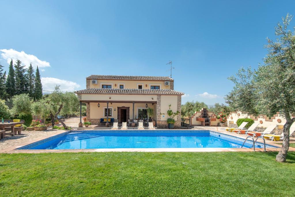 a villa with a swimming pool in front of a house at Hacienda Los Olivos in Ronda