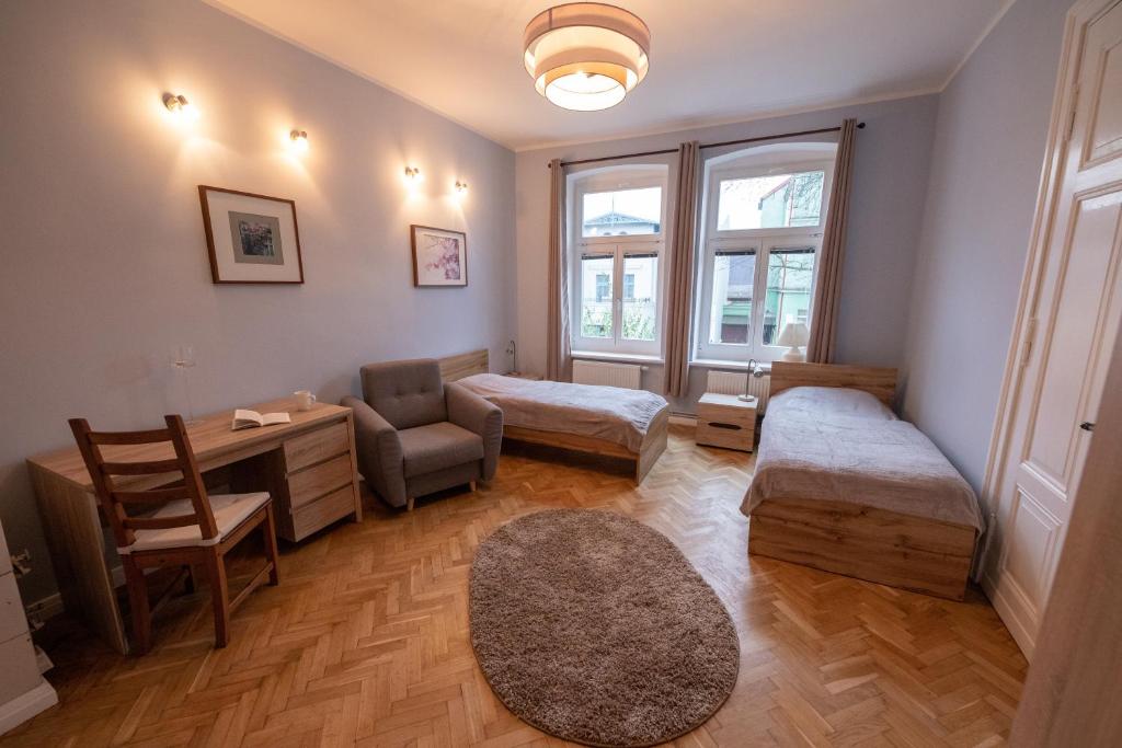 ソポトにあるVictus Apartamenty, Apartament Grandeのベッド2台、デスク、椅子が備わる客室です。
