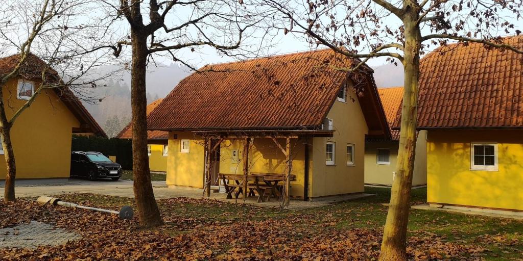 une maison jaune avec une table devant elle dans l'établissement Apartmajske hiške Lubadarček, à Podčetrtek