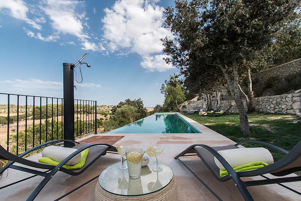 um pátio com uma mesa e cadeiras ao lado de uma piscina em Country House Sa Serra em Lloret de Vistalegre