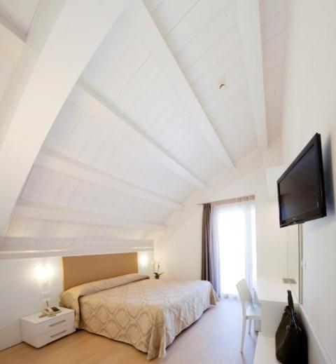 a bedroom with a bed and a flat screen tv at Hotel Lux in Caorle