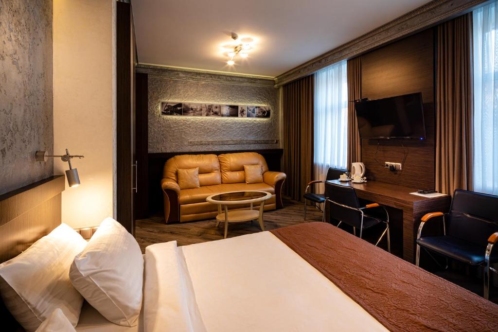 a hotel room with a bed and a couch and a desk at Biplan Hotel in Daugavpils