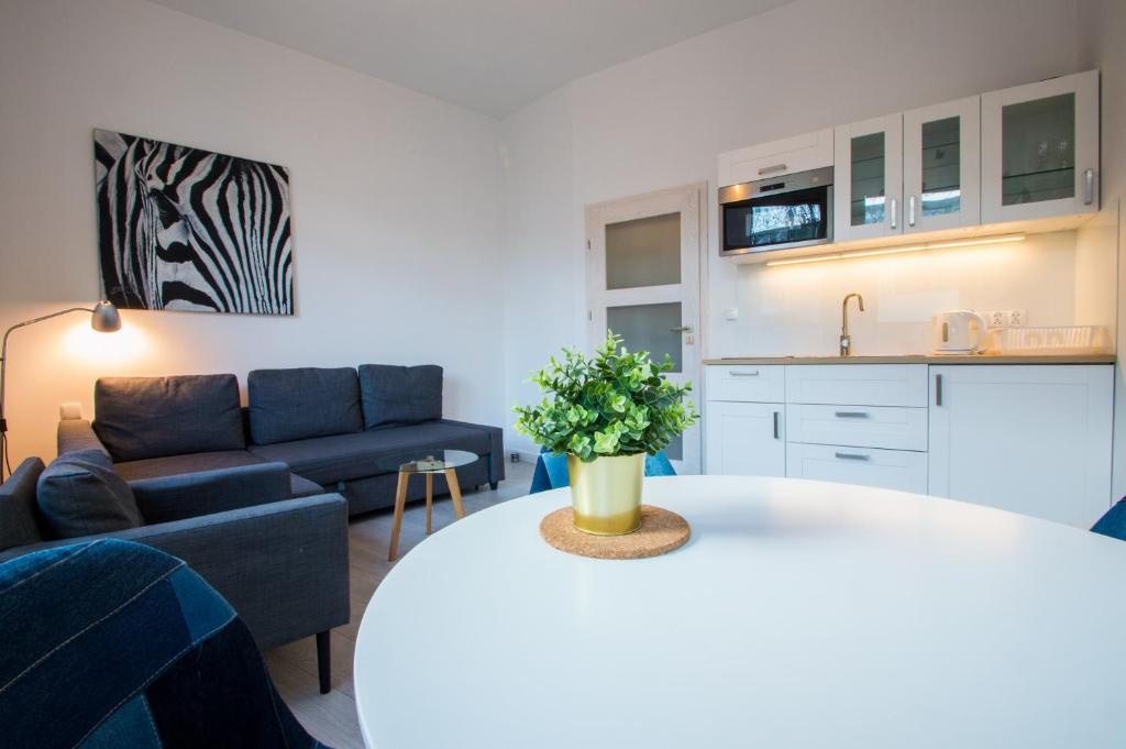 eine Küche und ein Wohnzimmer mit einem Sofa und einem Tisch in der Unterkunft Laguna Centrum by Grand Apartments in Sopot