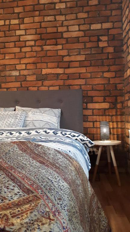 a bedroom with a brick wall and a bed and a table at Apartament Pogodny in Jelenia Góra