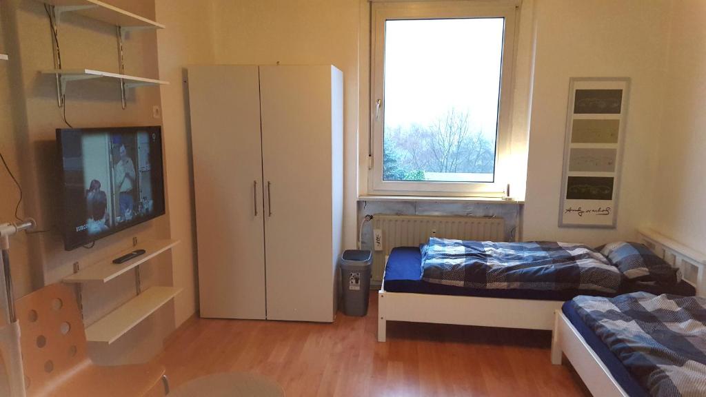 - une chambre avec un lit, une armoire et une télévision dans l'établissement Monteur Apartment Valeria, à Hagen