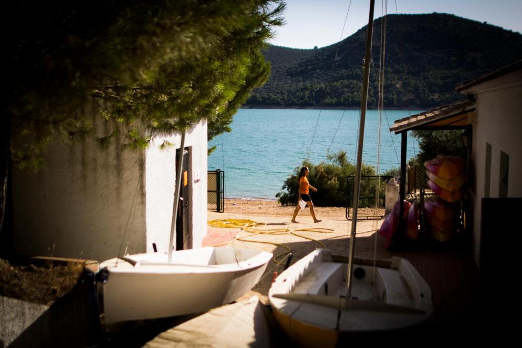 Una mujer caminando por la playa junto a un barco en CENTRO DE OCIO ALÚA Casa Rural Iznájar Lago de Andalucía, en Iznájar