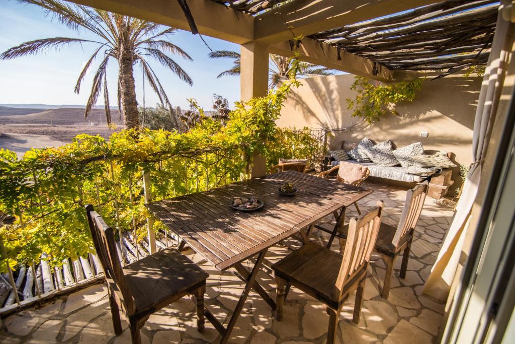 a wooden table and chairs on a patio with a view at Desert Home in Mitzpe Ramon