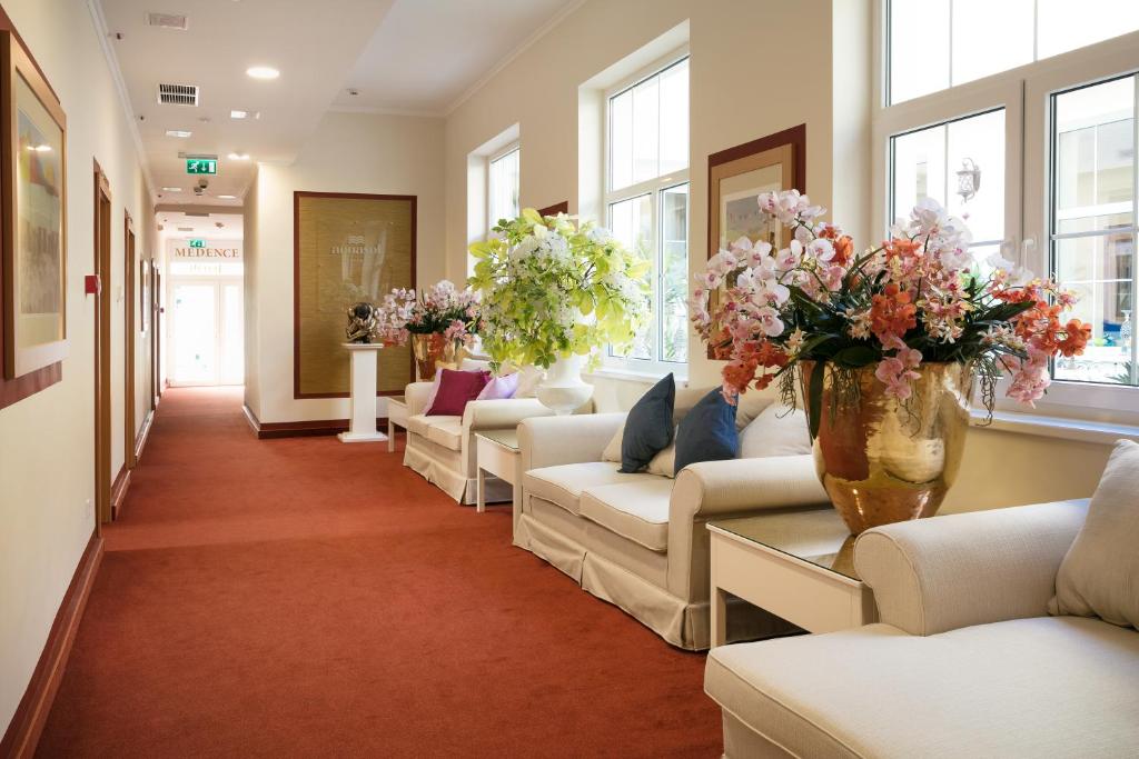 a waiting room with couches and vases of flowers at Aquasol Resort in Mosonmagyar&oacute;v&aacute;r