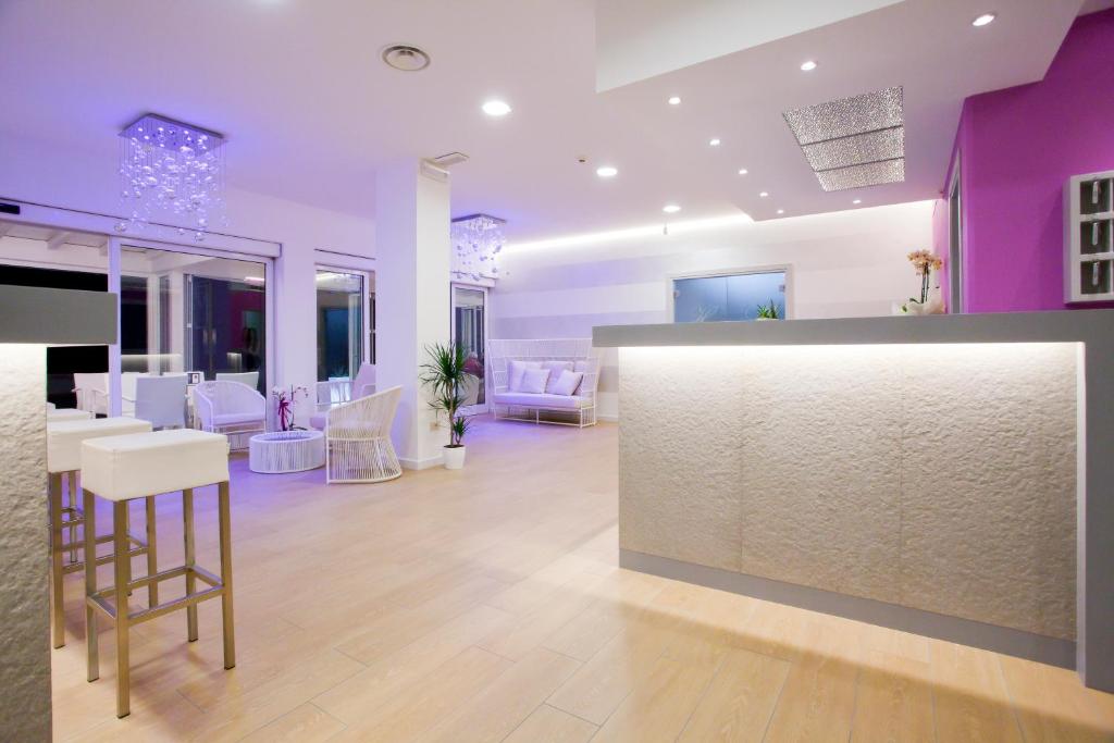 a room with a bar with pink and white furniture at Hotel Lux in Caorle