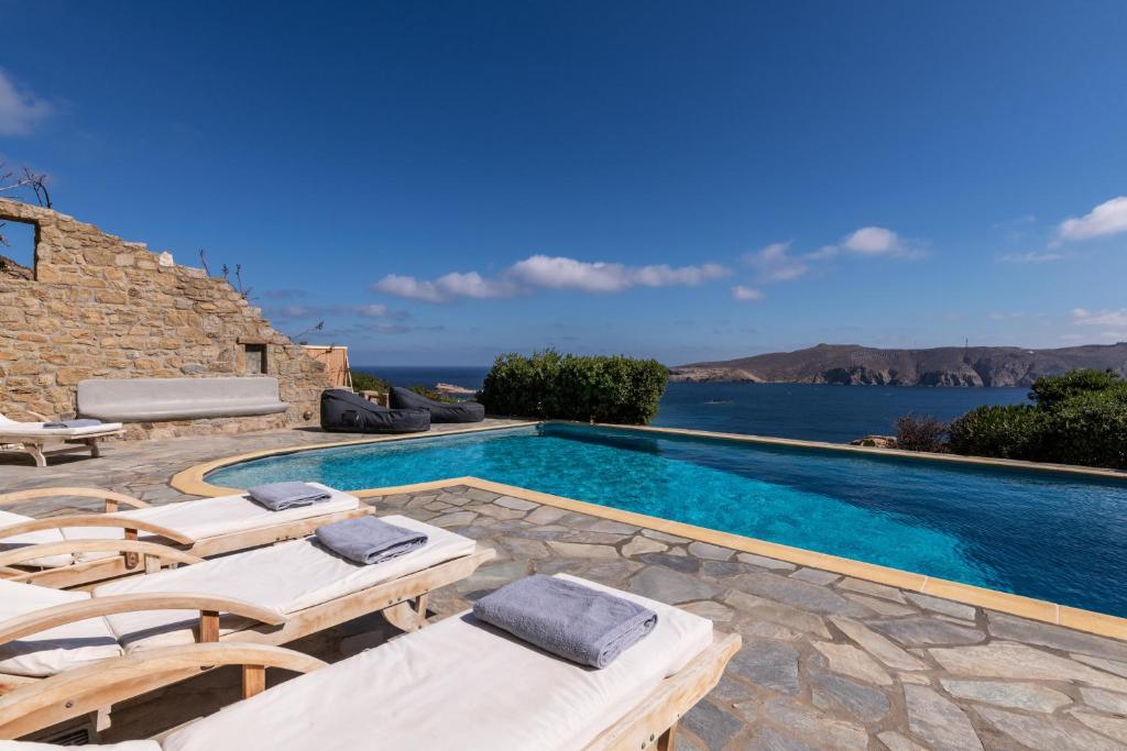 een zwembad met ligstoelen en een villa bij Summer Mood Villas (6 bedroom villa) in Mykonos-stad