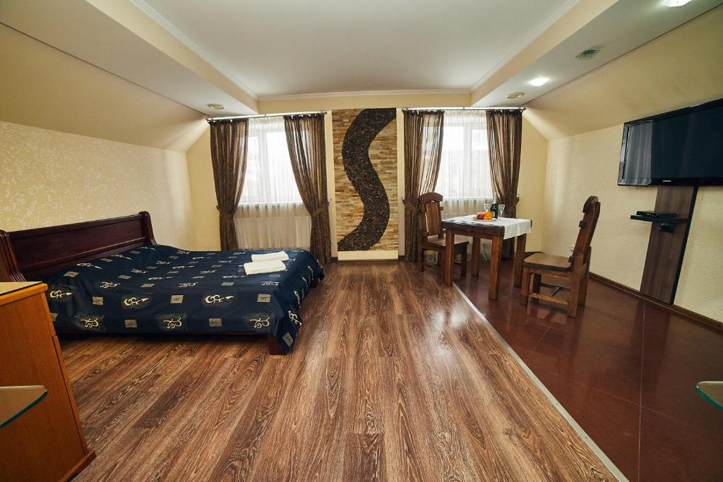a hotel room with a bed and a table and chairs at River in Vinnytsya