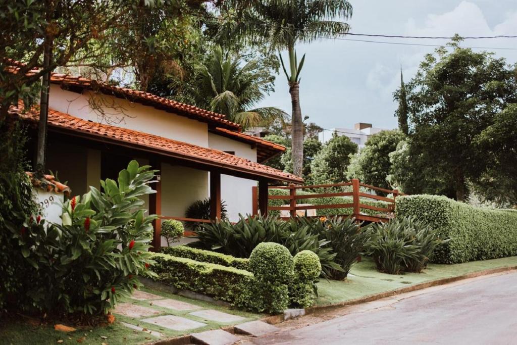 ein Haus mit einem Zaun und einigen Büschen und Bäumen in der Unterkunft Casa em Capitólio - Escarpas do Lago in Capitólio
