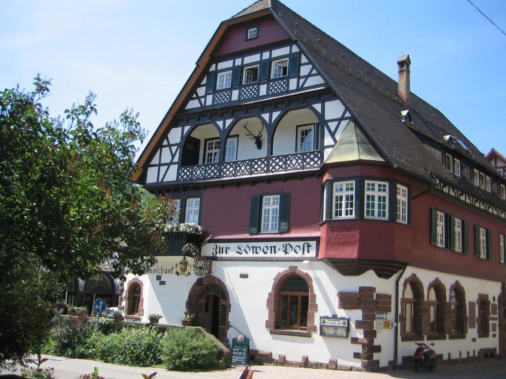 un edificio con una señal que lee el pasado rápido en Löwen-Post, en Alpirsbach