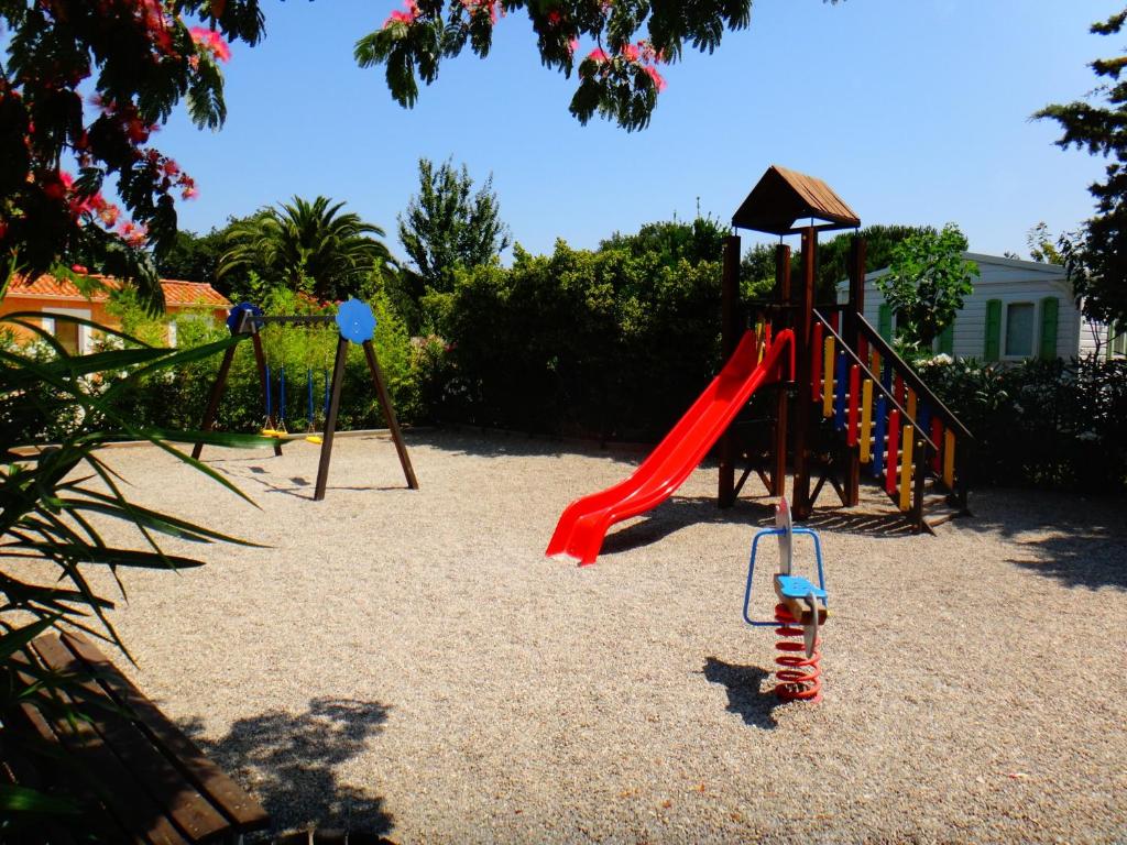 a playground with a red slide and swings at Domaine La Pinède Enchantée in Argelès-sur-Mer